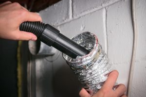 Technician vacuuming dryer vent to remove lint